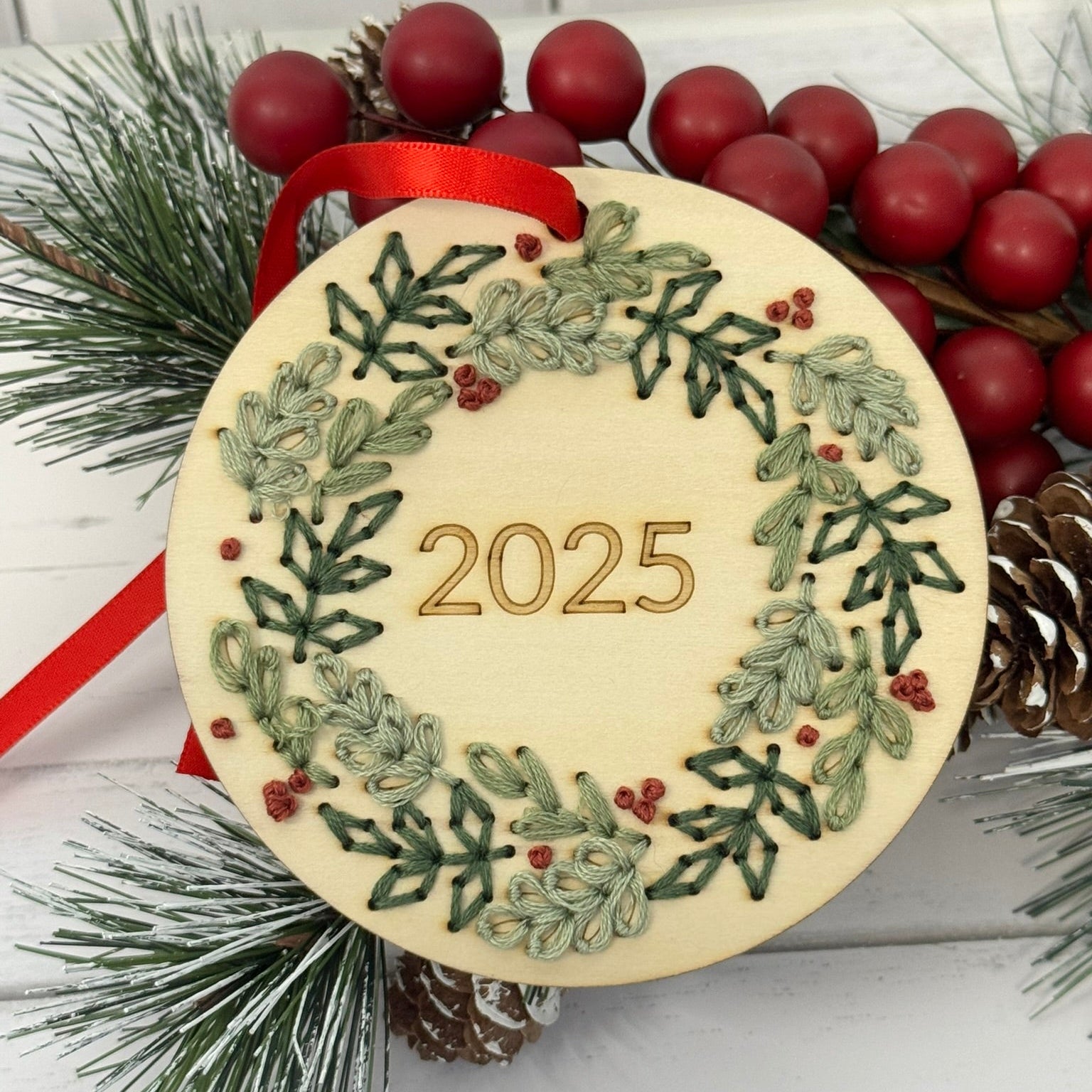 Decorative ornament with 2025 and wreath design, surrounded by Christmas elements on a white background.