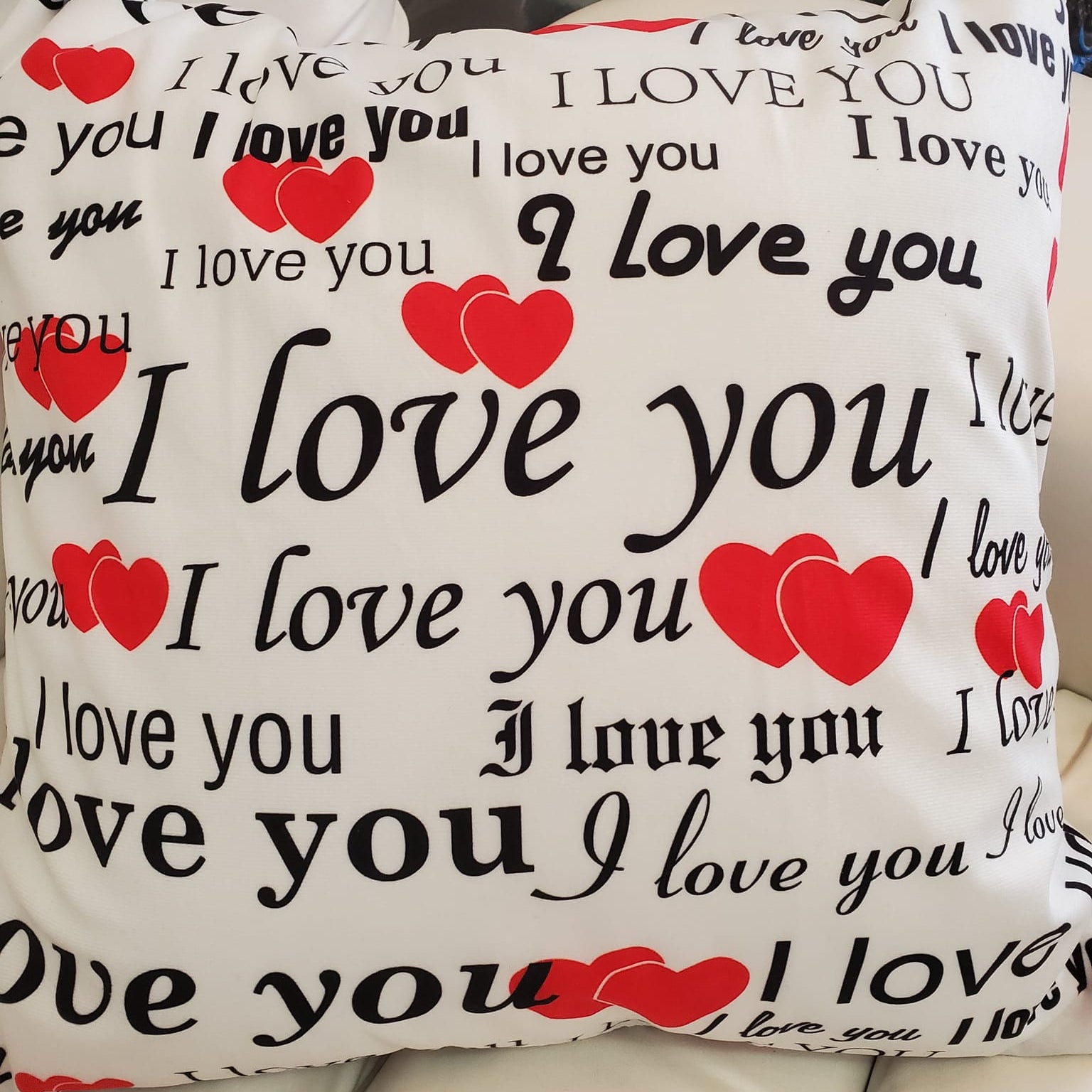 Pillow with 'I love you' text and red hearts on a white background